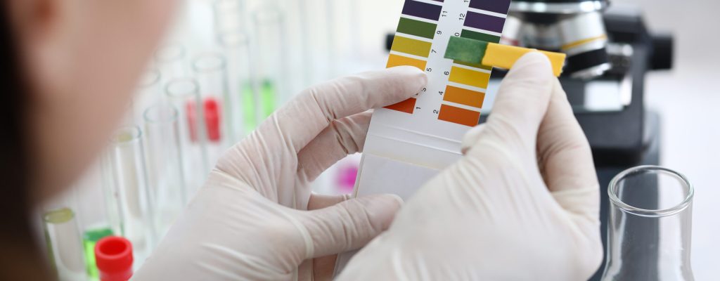 Scientist doing comparison of two test Close-up of hands of chemist comparing colors with samples. Researcher making mixture of fluid for experiment in laboratory. Chemical experiments concept